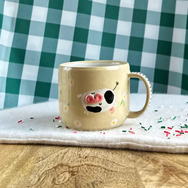 kubek krówki wśród stokrotek