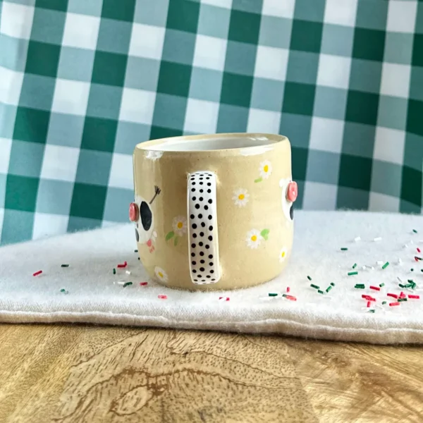 kubek krówki wśród stokrotek