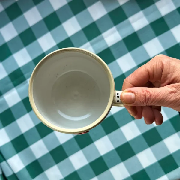 kubek krówki wśród stokrotek